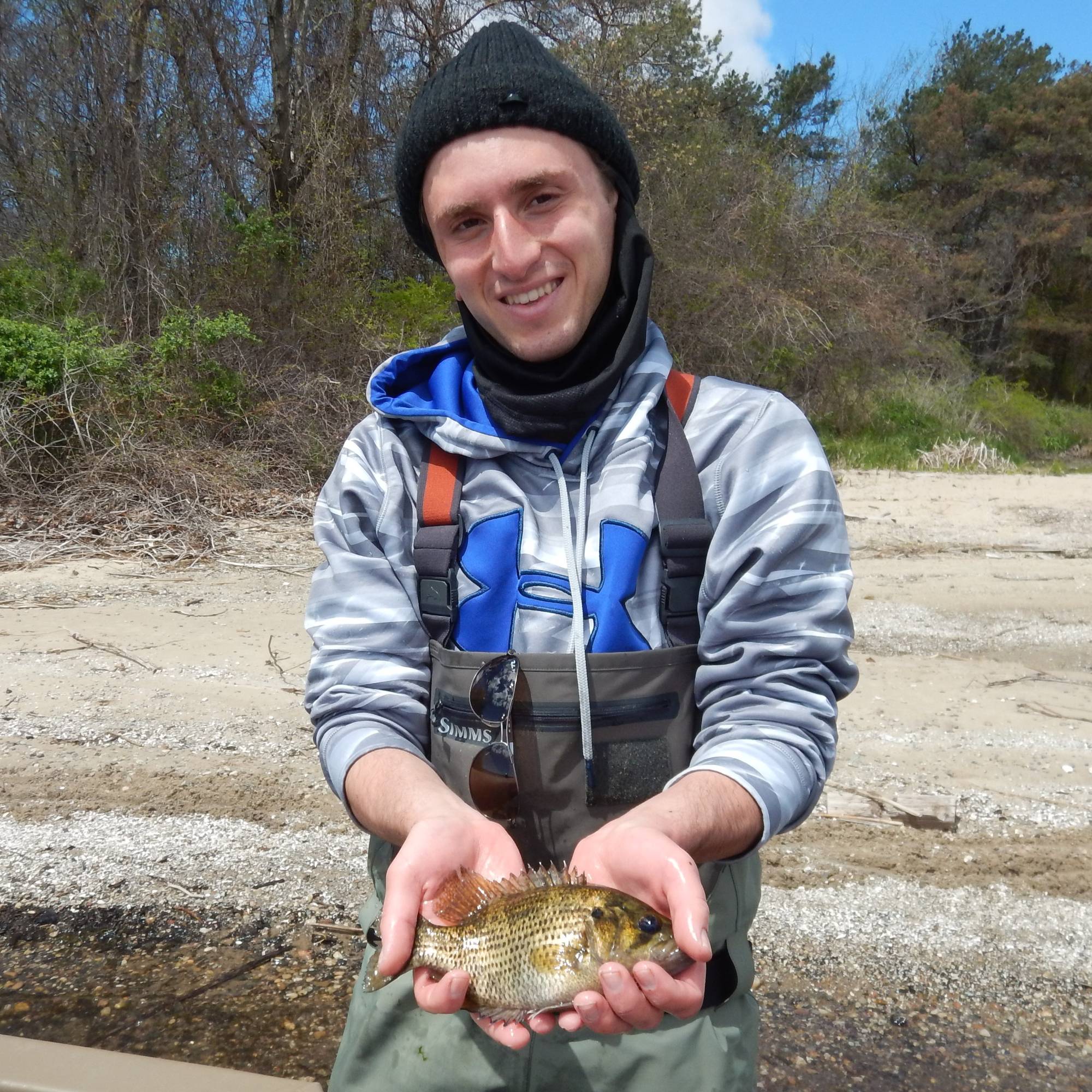 A student is holding a rock bass (fish) that was captured using a fyke net.